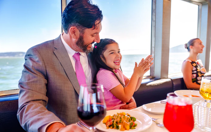 Father and daughter enjoying a meal on a San Francisco dinner cruise.