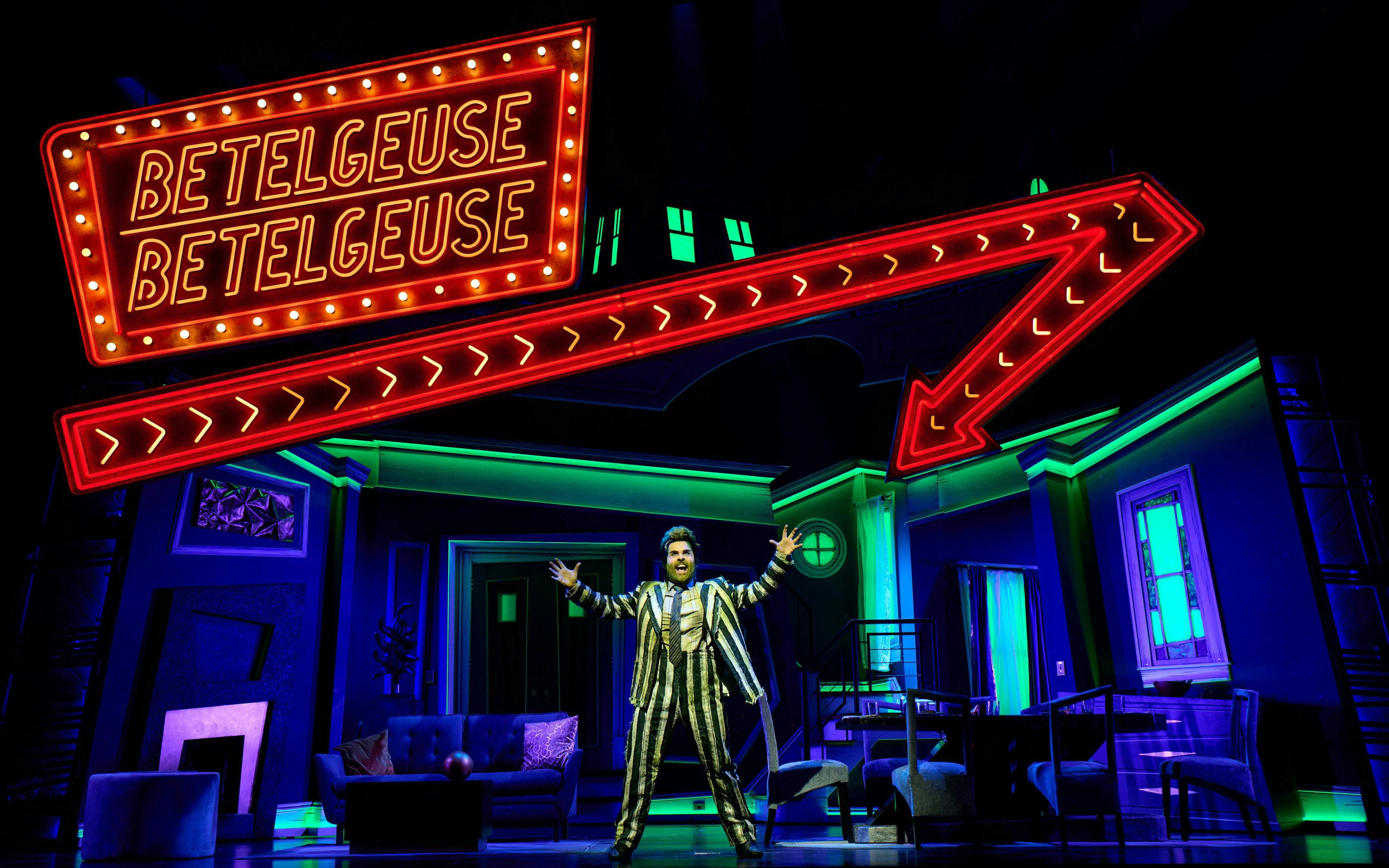 Beetlejuice musical performance with neon sign on West End stage.