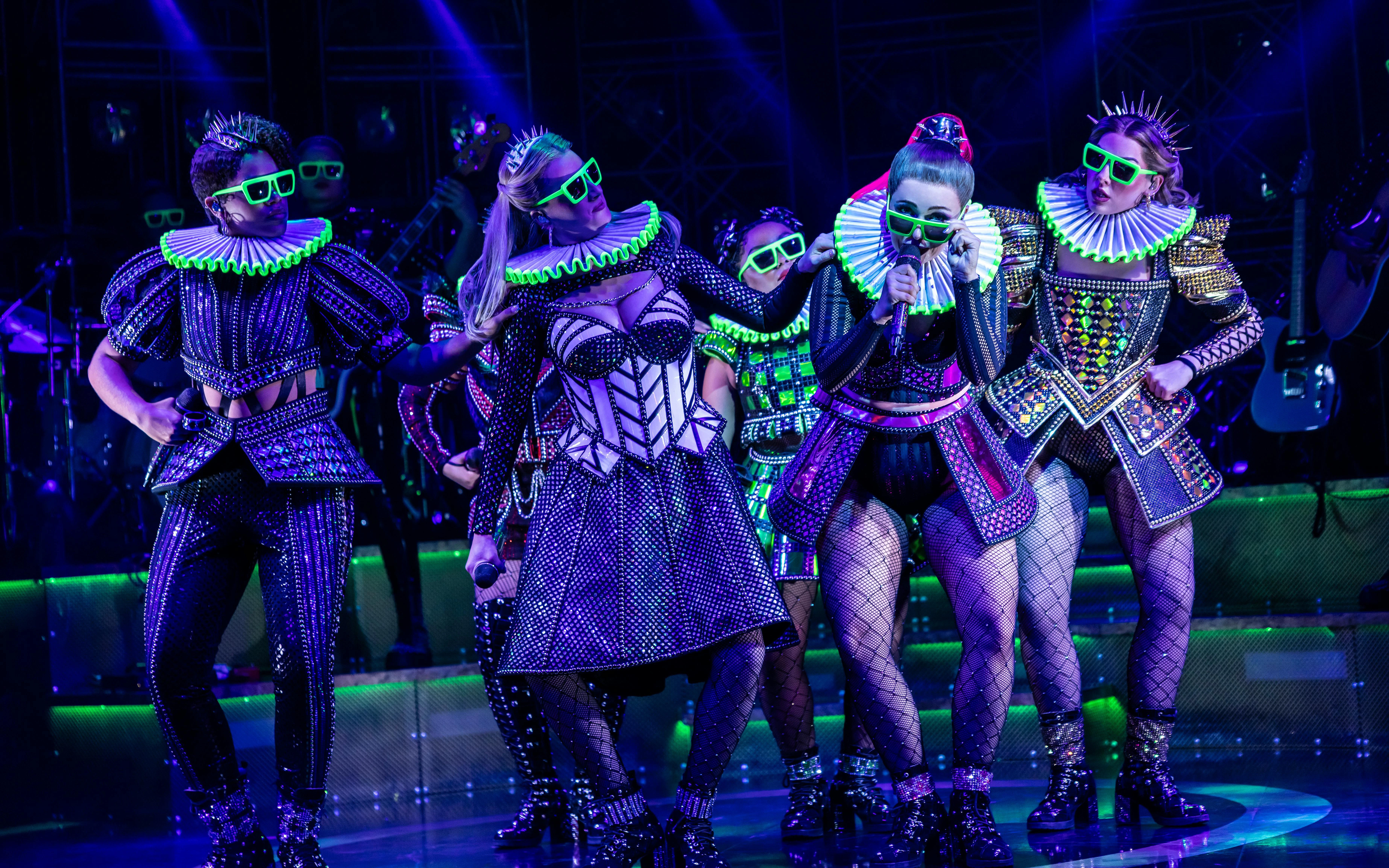 Performers in vibrant costumes on stage during Six musical in West End.