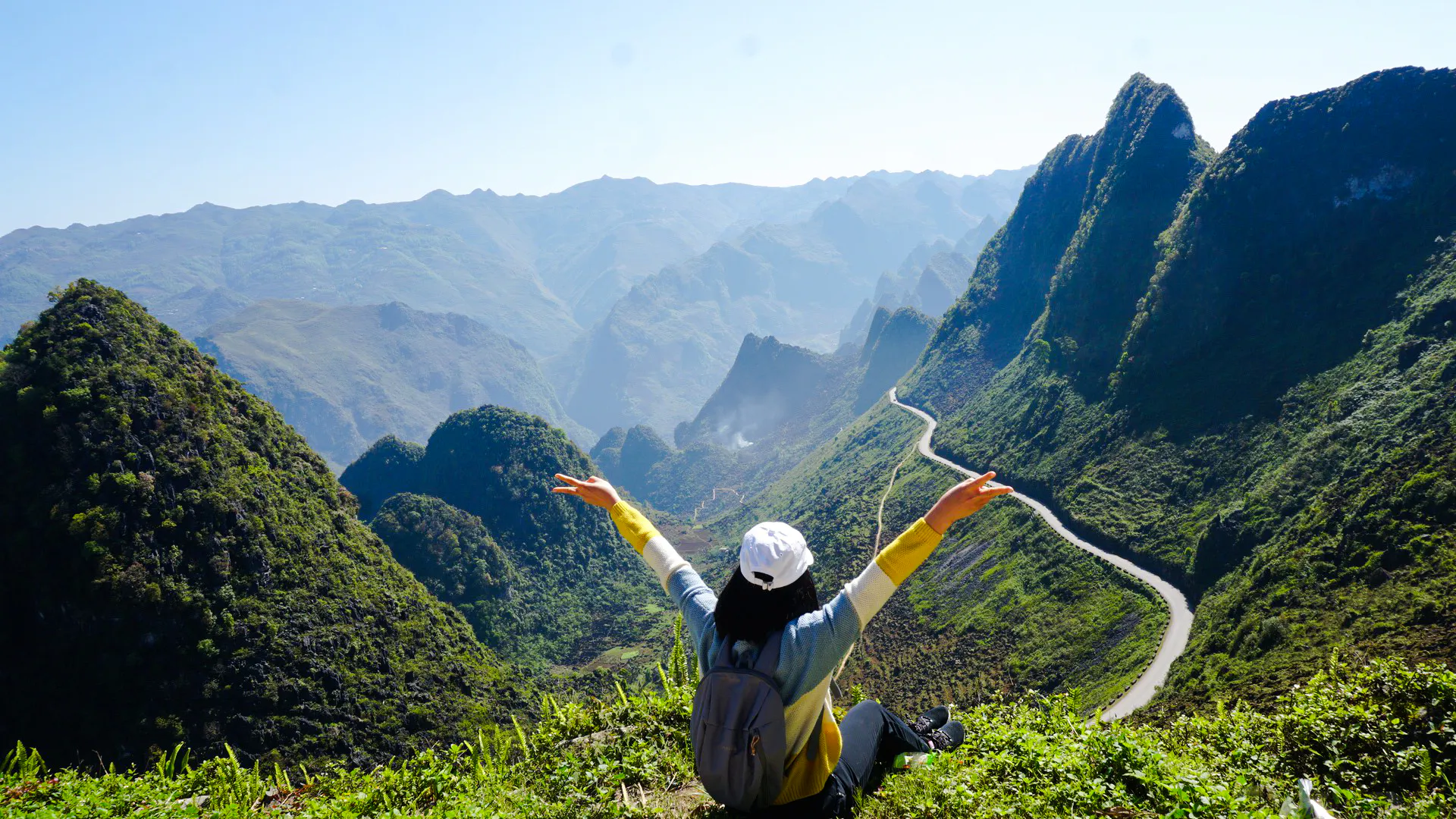 Trekker overlooking lush mountains and winding road in Ba Vi National Park, Hanoi.