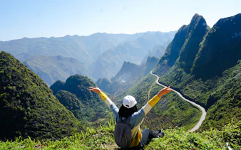 Trekker overlooking lush mountains and winding road in Ba Vi National Park, Hanoi.