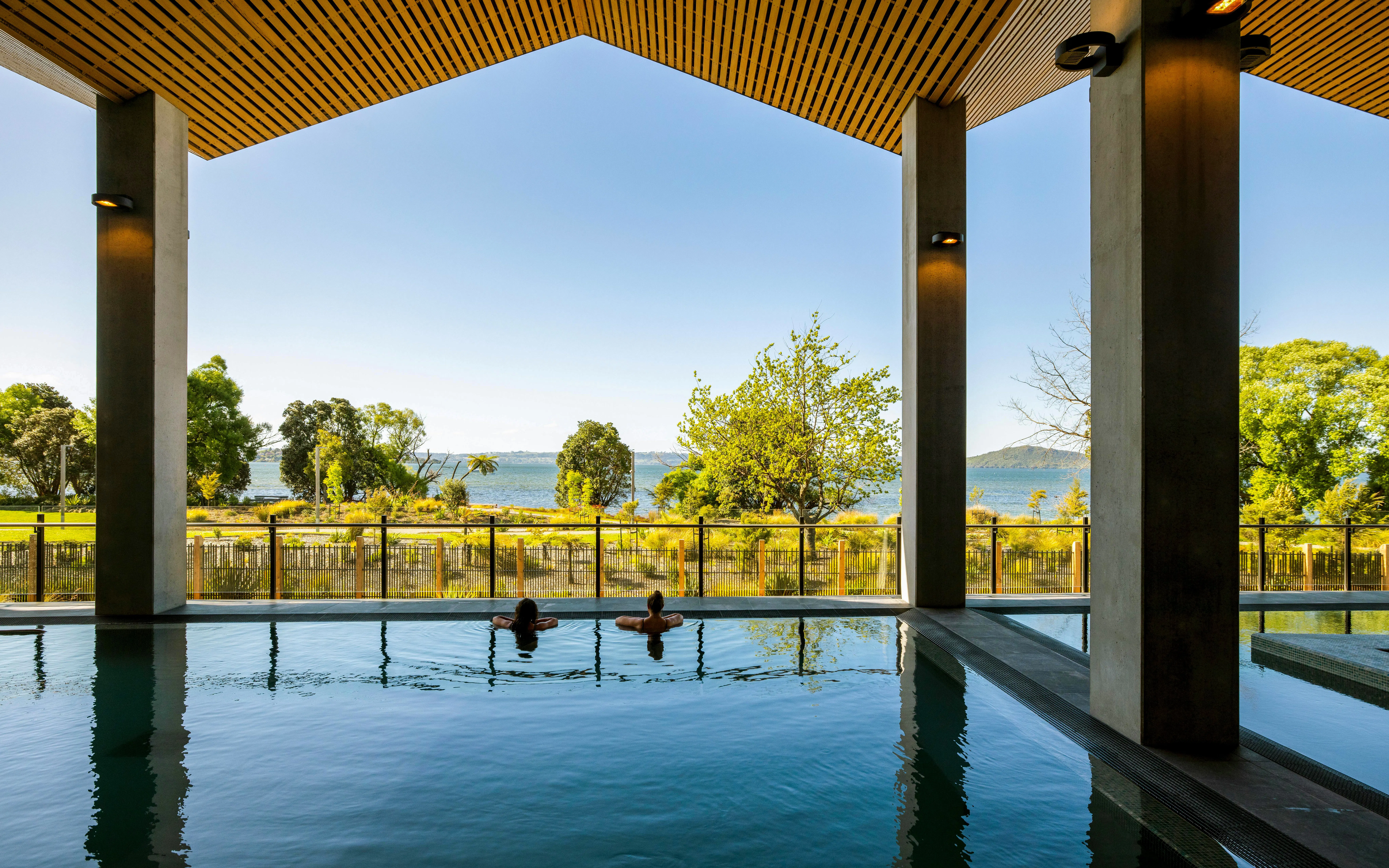 Two people relaxing in a hydropool with a view of Lake Rotorua at Wai Ariki Hot Springs & Spa.