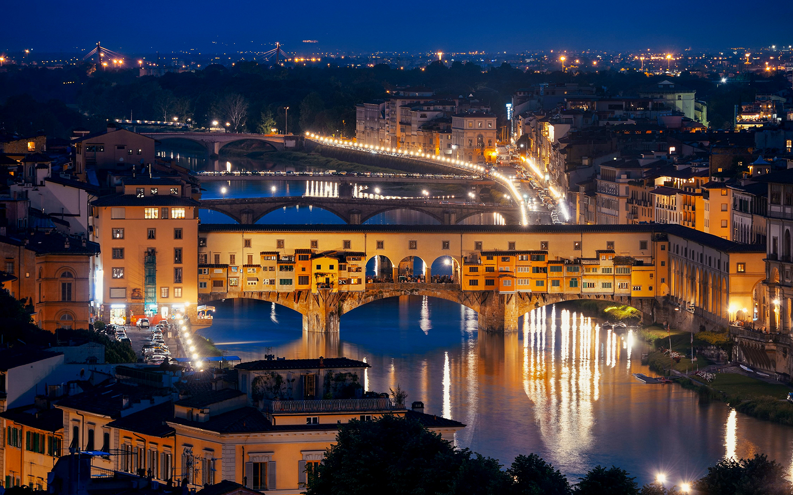 Ponte Vecchio illuminated at night over the Arno River in Florence, Italy.