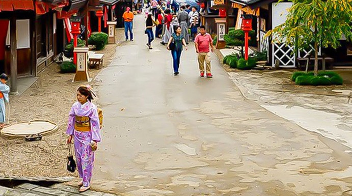Visitors walking through Edo Wonderland, Japan, with traditional buildings and mountainous backdrop.