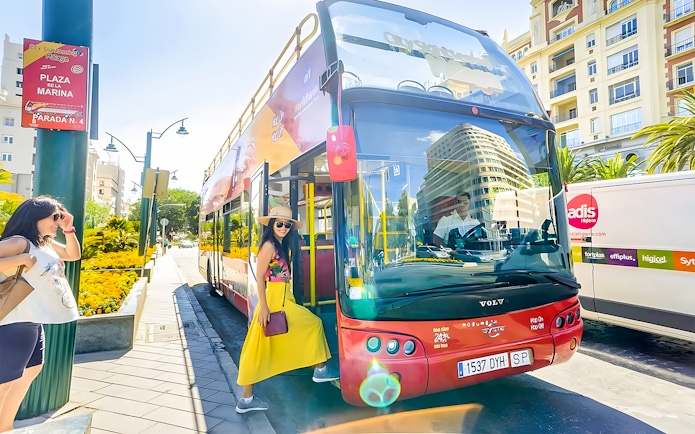 Woman boarding City Sightseeing hop-on hop-off bus at Plaza de la Marina, Malaga.