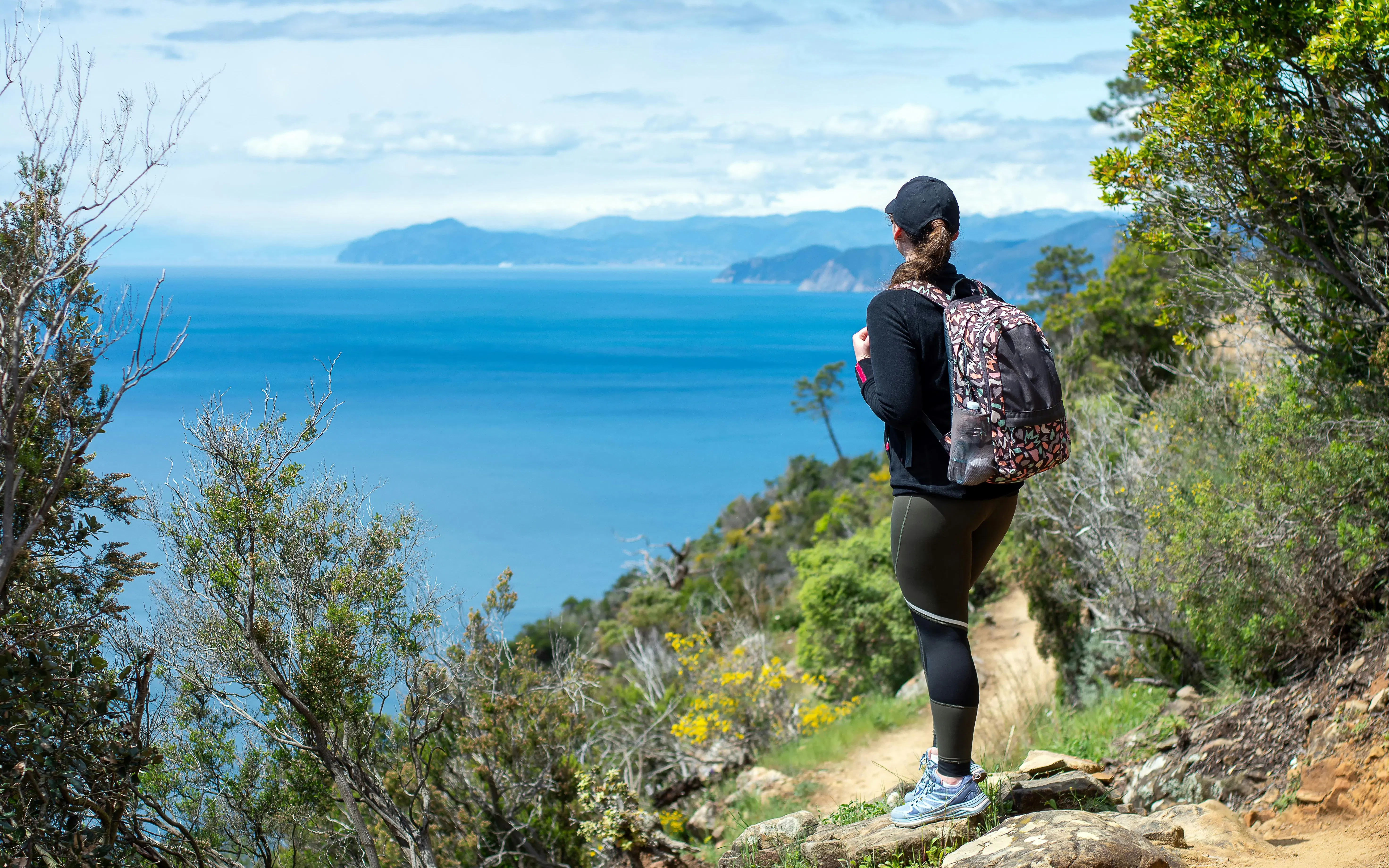 Hiker with backpack on Levanto to Cinque Terre trail overlooking the sea.