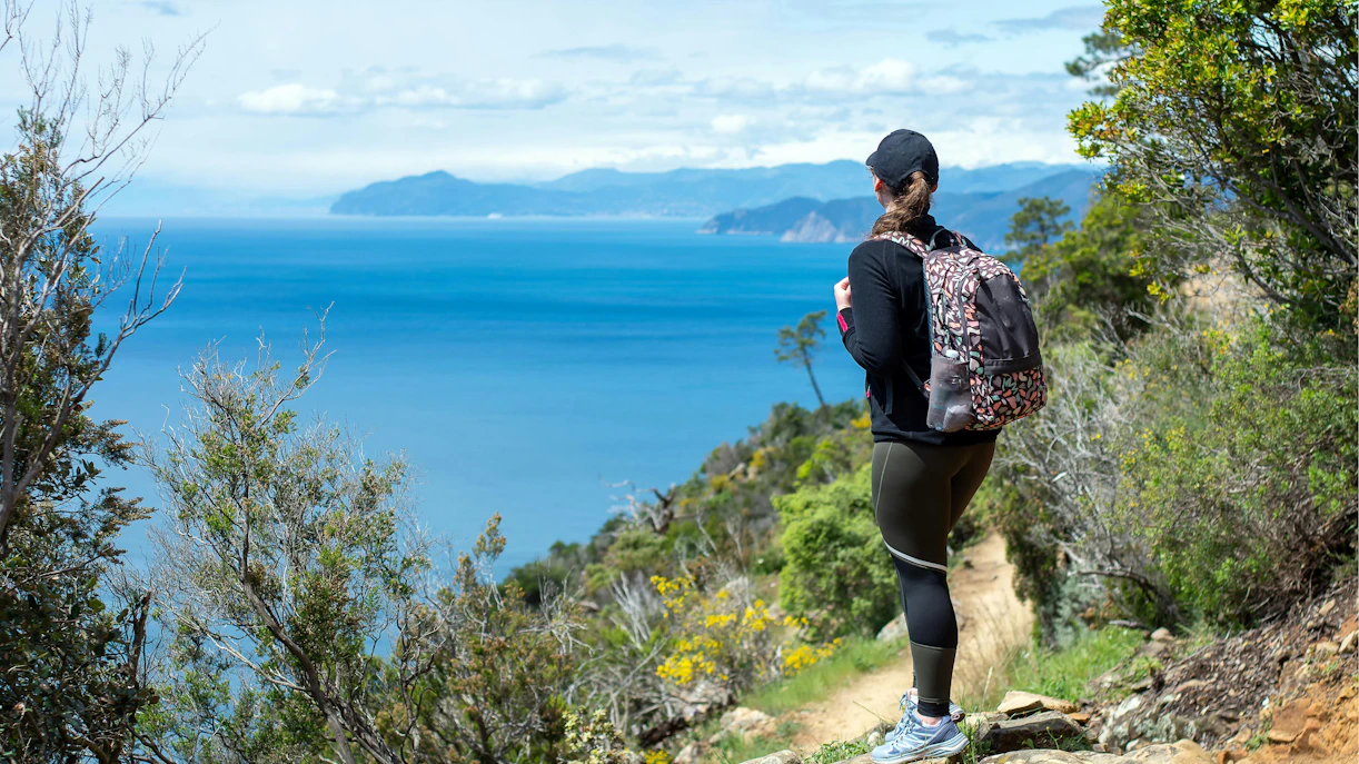 Hiker with backpack on Levanto to Cinque Terre trail overlooking the sea.