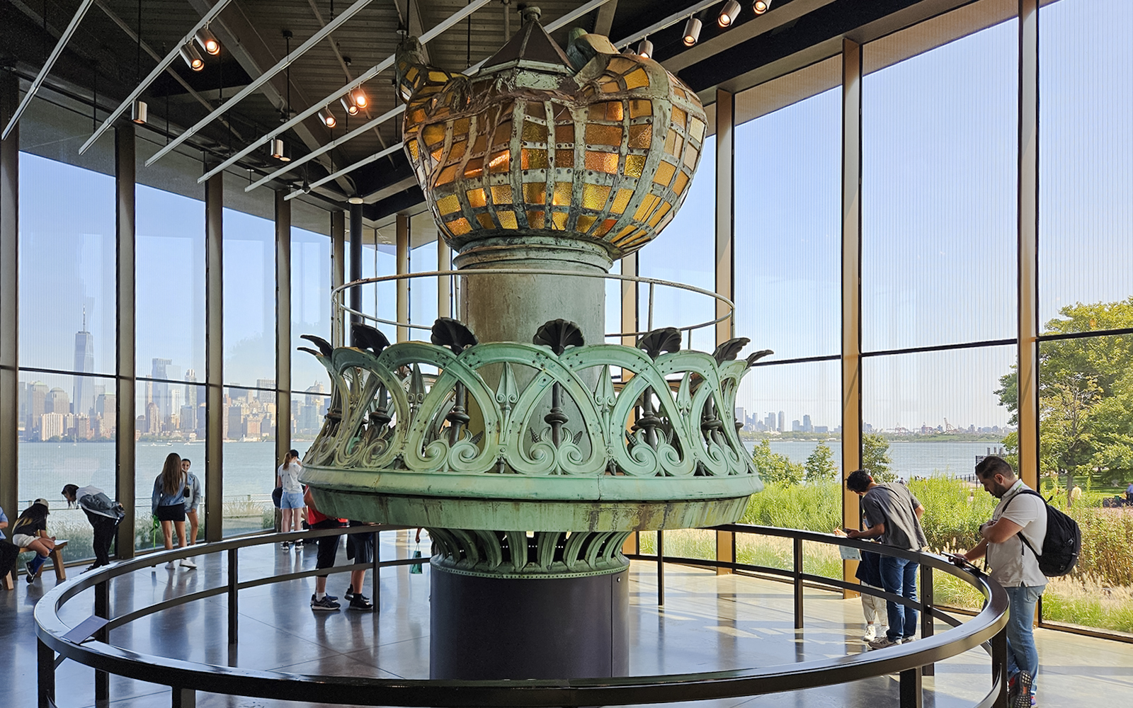 Original torch and crown spikes from the Statue of Liberty displayed indoors with city skyline view.