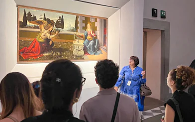 Visitors observing a painting during a guided Uffizi Gallery private tour in Florence.