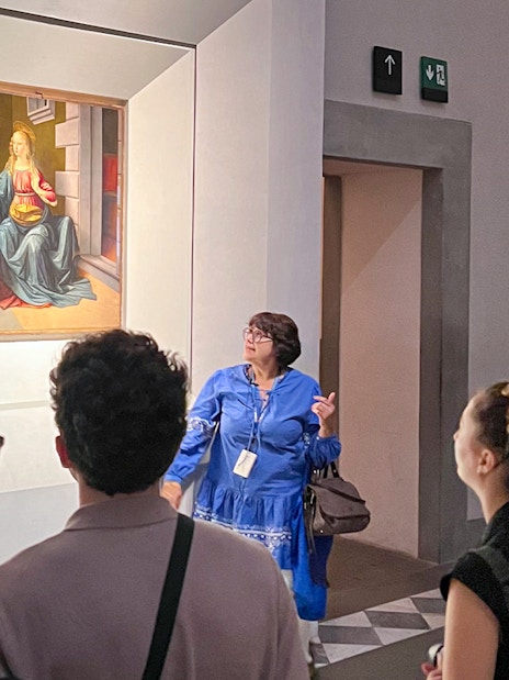 Visitors observing a painting during a guided Uffizi Gallery private tour in Florence.