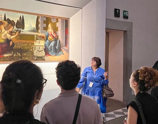 Visitors observing a painting during a guided Uffizi Gallery private tour in Florence.