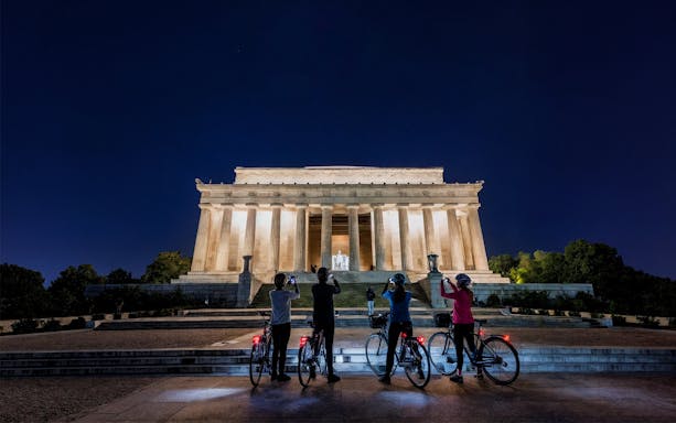 Tourists on bikes photographing the Lincoln Memorial at night in Washington D.C.