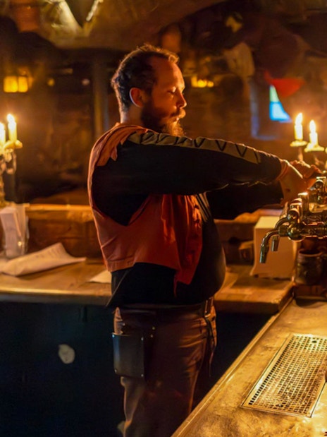 Bartender serving beer at Dětenice Brewery during medieval dinner show near Prague.