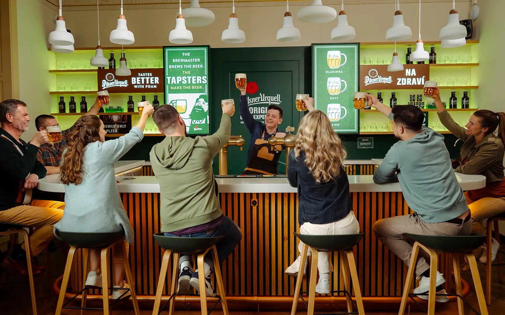 Group enjoying beer tasting at Pilsner Urquell bar in Prague.