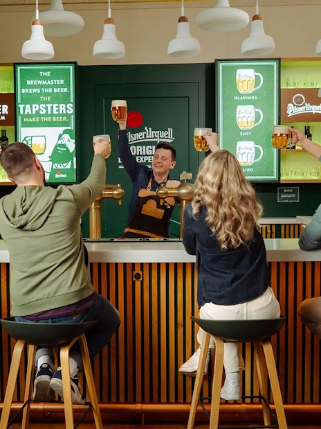 Group enjoying beer tasting at Pilsner Urquell bar in Prague.