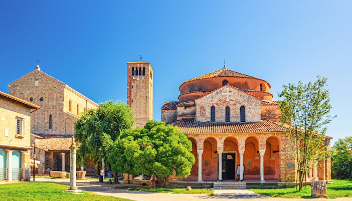 Murano glassblower crafting art, colorful Burano houses, Torcello's historic church in full-day island tour.