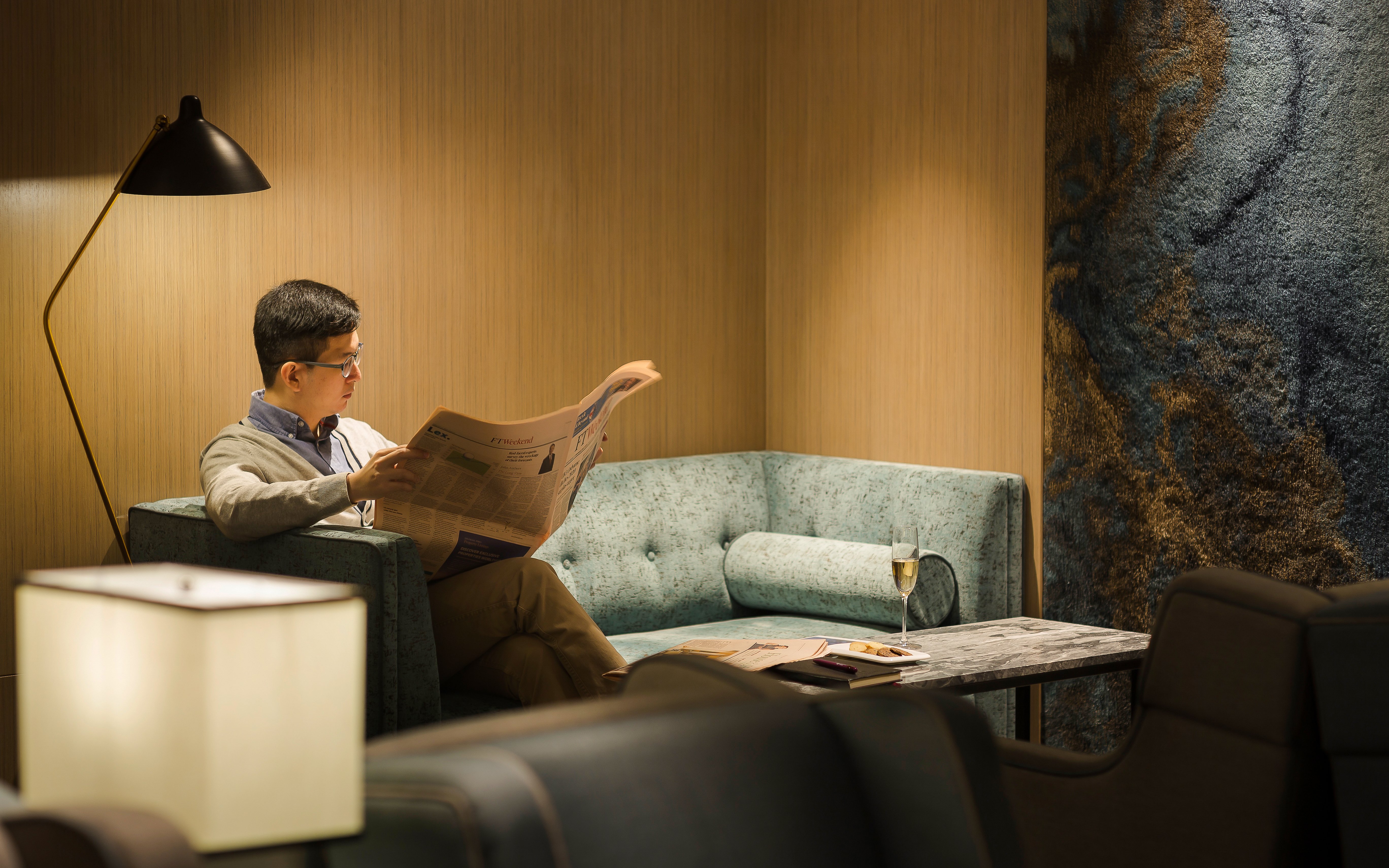 Man reading newspaper in Plaza Premium Lounge, Zone D, Taipei, Taiwan.