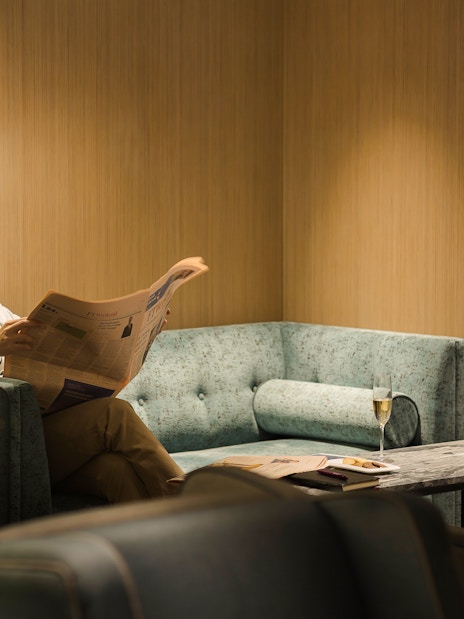 Man reading newspaper in Plaza Premium Lounge, Zone D, Taipei, Taiwan.