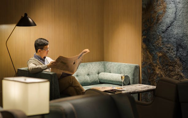 Man reading newspaper in Plaza Premium Lounge, Zone D, Taipei, Taiwan.