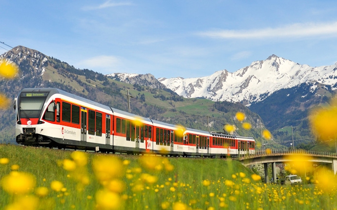 Lucerne–Interlaken Express train with snow-capped mountains in the background.