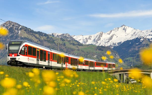 Lucerne–Interlaken Express train with snow-capped mountains in the background.