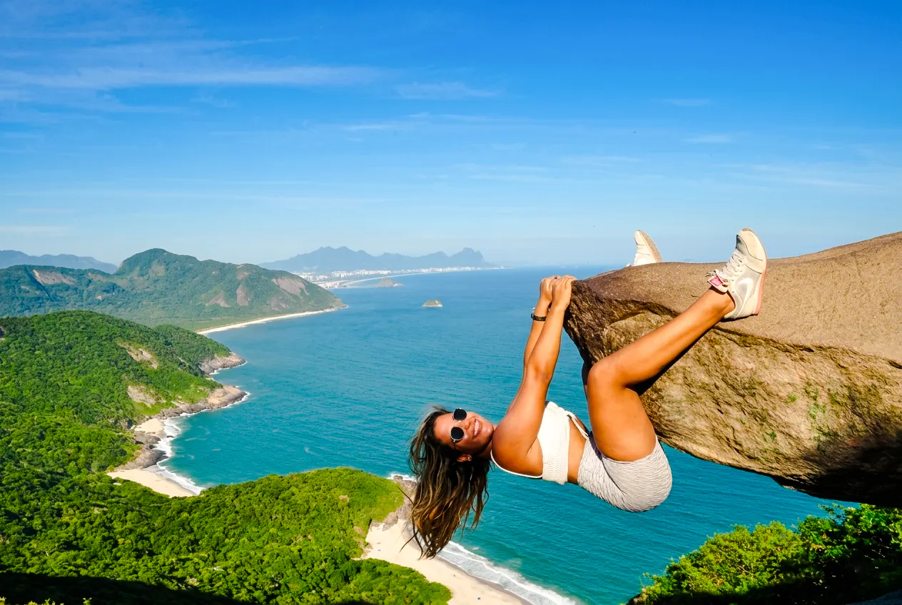 Person posing on Telegraph Stone with ocean and forest views, Rio de Janeiro.