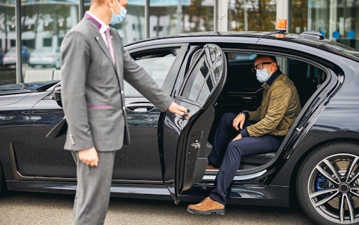 Chauffeur opening car door for passenger at Katowice Pyrzowice Airport.