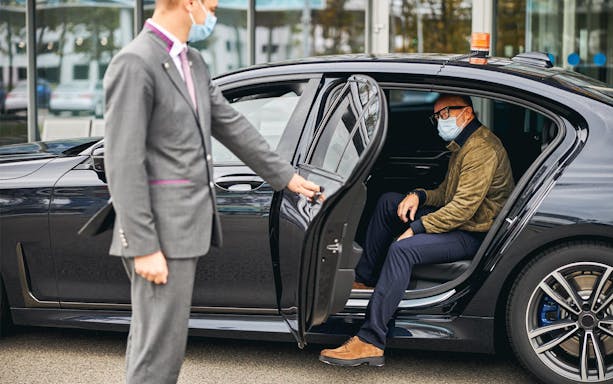 Chauffeur opening car door for passenger at Katowice Pyrzowice Airport.