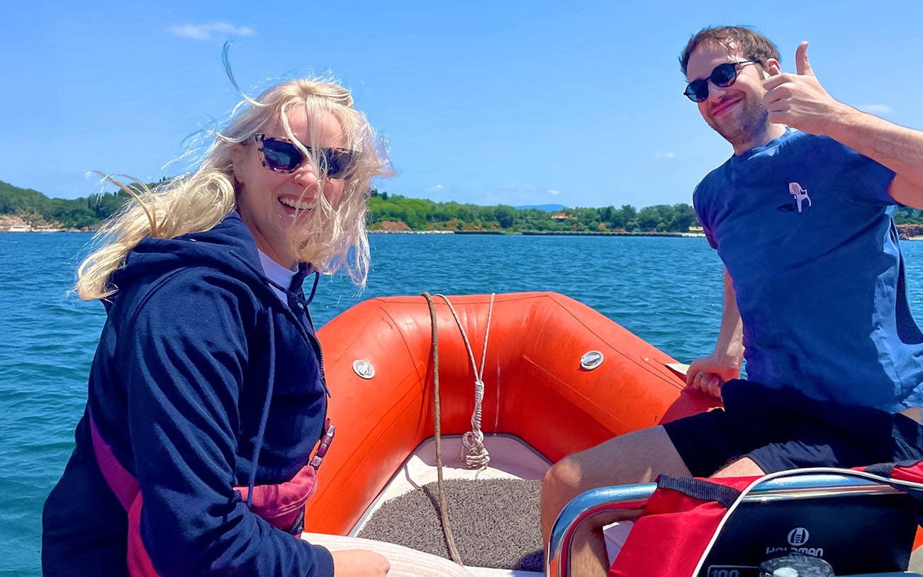 Guests smiling on a speedboat ride with scenic coastline in the background.