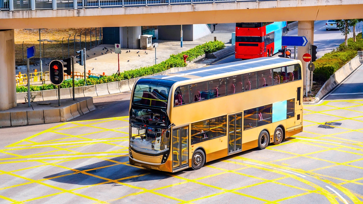 Double-decker bus at a Hong Kong intersection, aerial view.