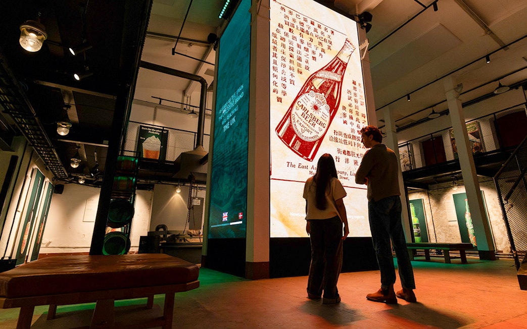 Visitors viewing Carlsberg beer exhibit inside Home of Carlsberg museum.