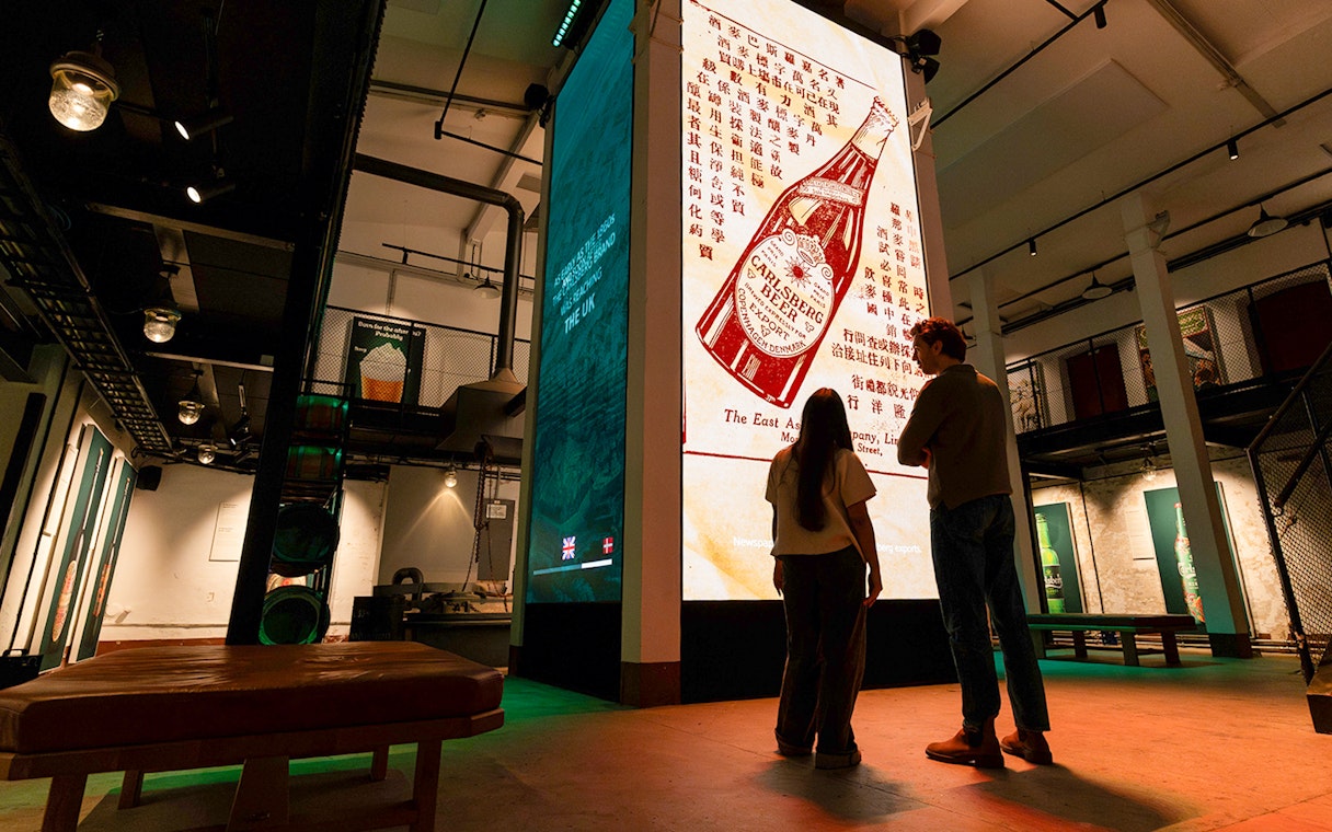 Visitors viewing Carlsberg beer exhibit inside Home of Carlsberg museum.