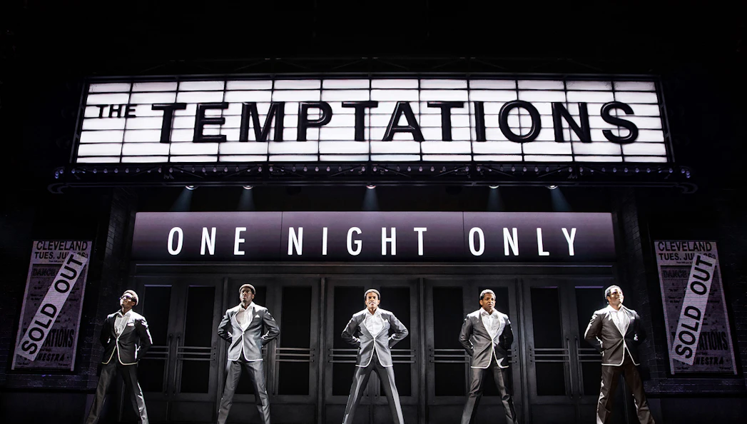 The Temptations musical performance, Ain't Too Proud, on stage with marquee sign.