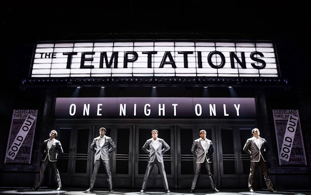 The Temptations musical performance, Ain't Too Proud, on stage with marquee sign.