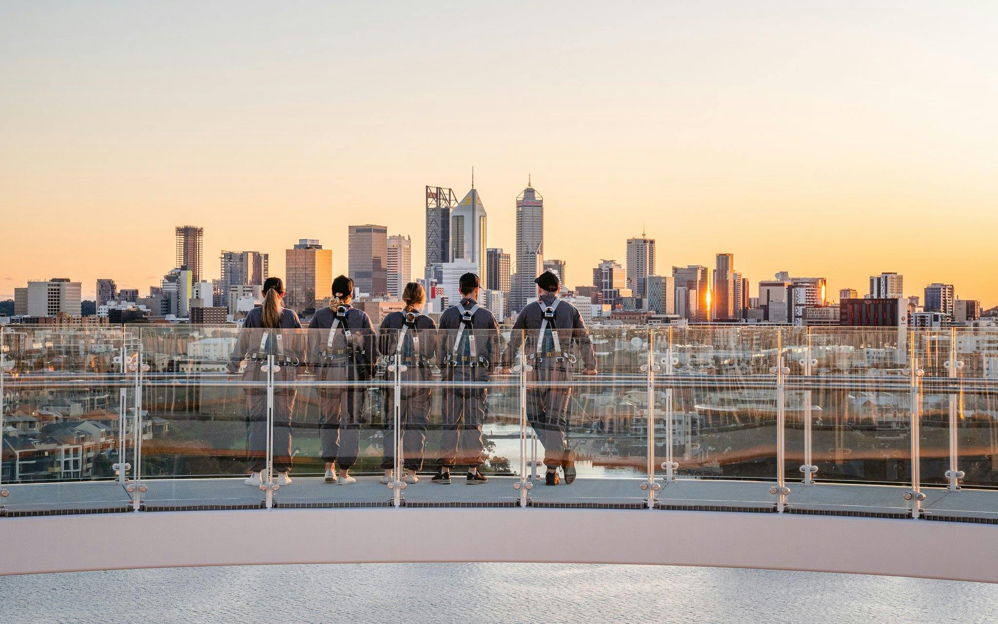 Group on rooftop viewing Perth skyline at sunset during Vertigo by Twilight tour.