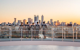 Group on rooftop viewing Perth skyline at sunset during Vertigo by Twilight tour.