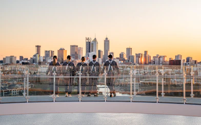 Group on rooftop viewing Perth skyline at sunset during Vertigo by Twilight tour.