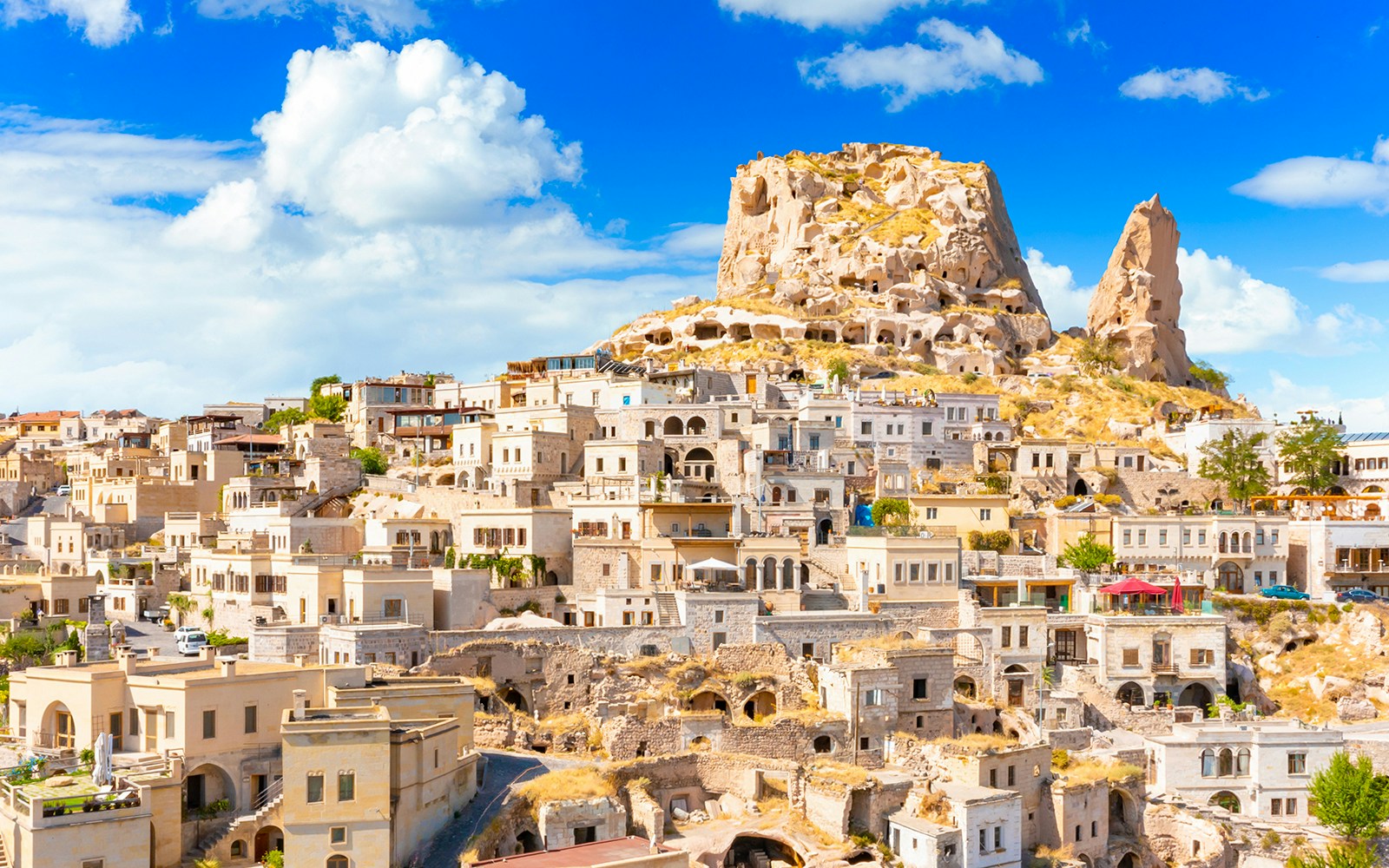 Uchisar Castle in Cappadocia with surrounding cave dwellings and stone houses.