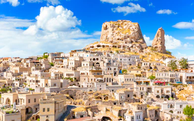 Uchisar Castle in Cappadocia with surrounding cave dwellings and stone houses.