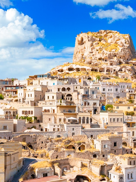 Uchisar Castle in Cappadocia with surrounding cave dwellings and stone houses.
