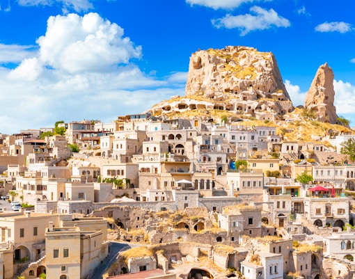 Uchisar Castle in Cappadocia with surrounding cave dwellings and stone houses.