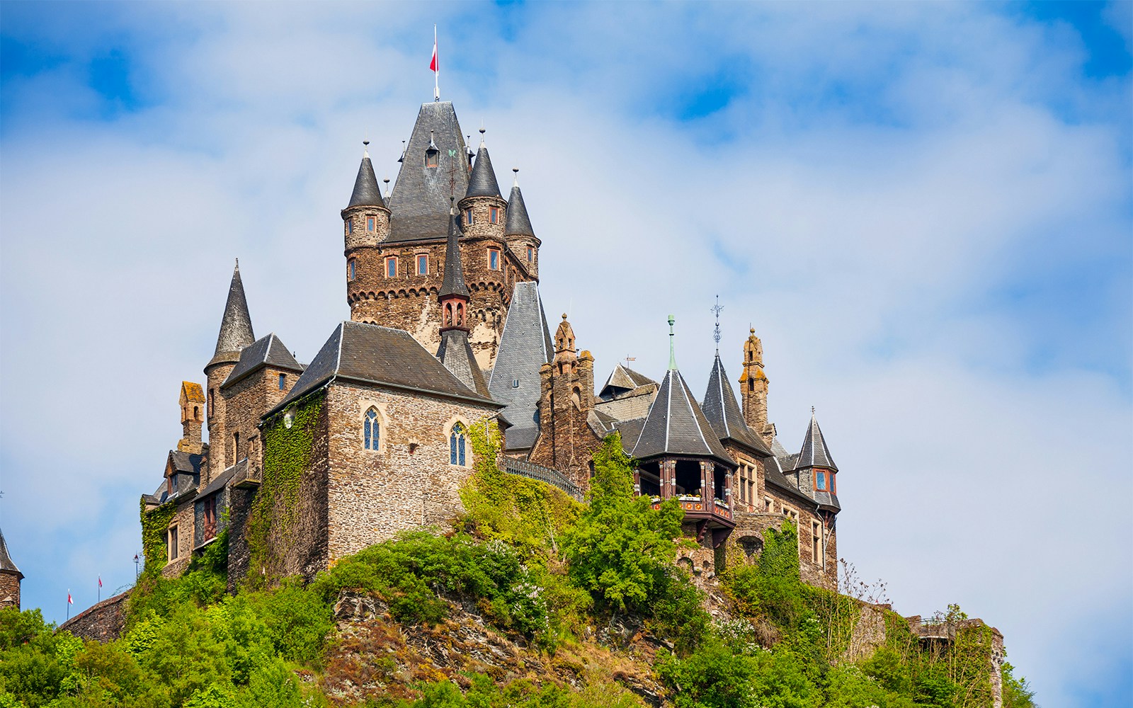 Mit Efeu bewachsene Burg Cochem auf einem Berg bei bewölktem Himmel