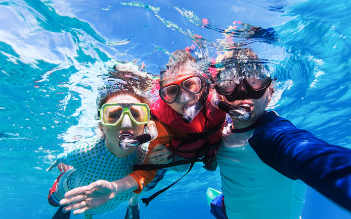 Father and sons snorkeling in clear reef waters.