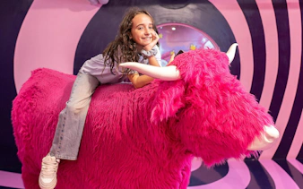 Child on pink furry sculpture at Big Fun Museum, Barcelona exhibit.