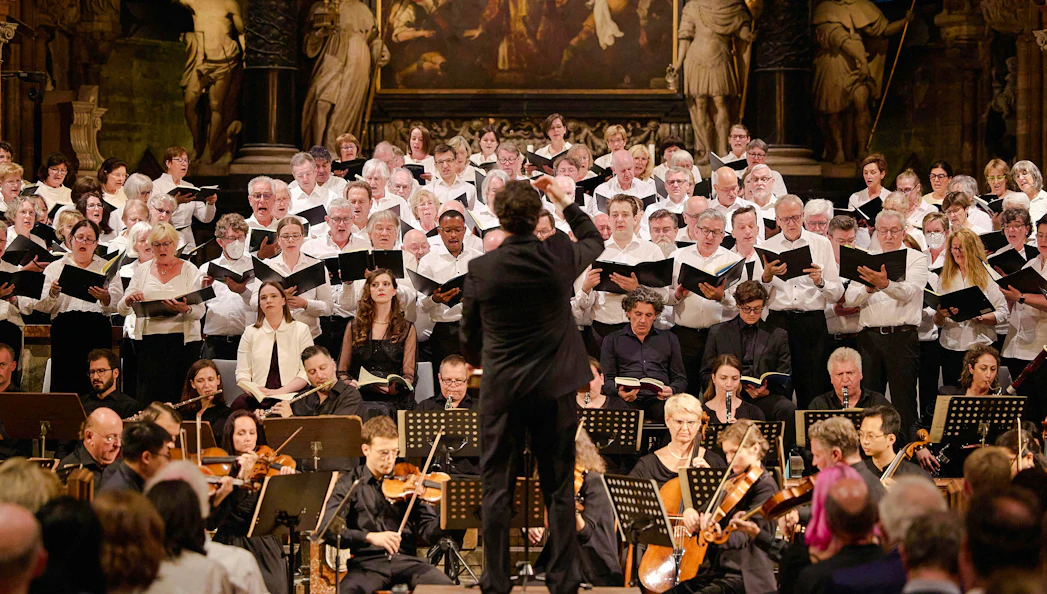 Choir performing inside St. Stephen's Cathedral Vienna with conductor and orchestra.
