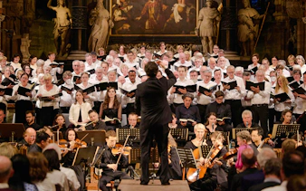 Choir performing inside St. Stephen's Cathedral Vienna with conductor and orchestra.