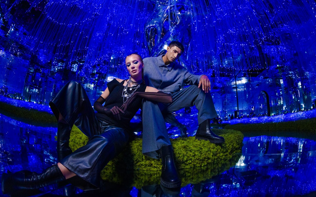 Two people posing in a futuristic, blue-lit room at AYA Universe.