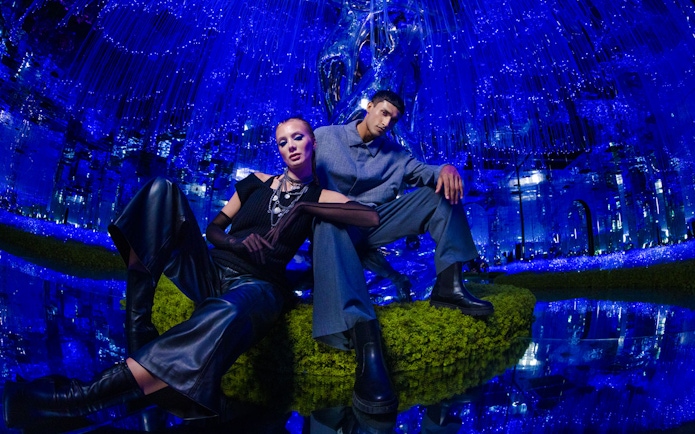 Two people posing in a futuristic, blue-lit room at AYA Universe.