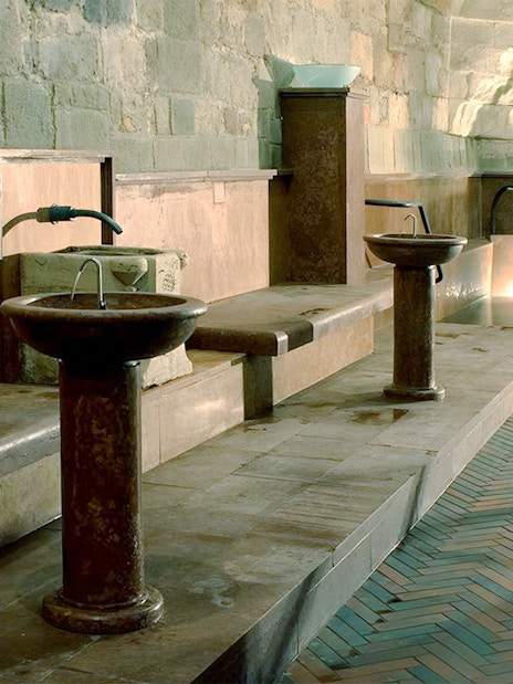 Rudas Thermal Spa interior with stone basins and illuminated pool at night.