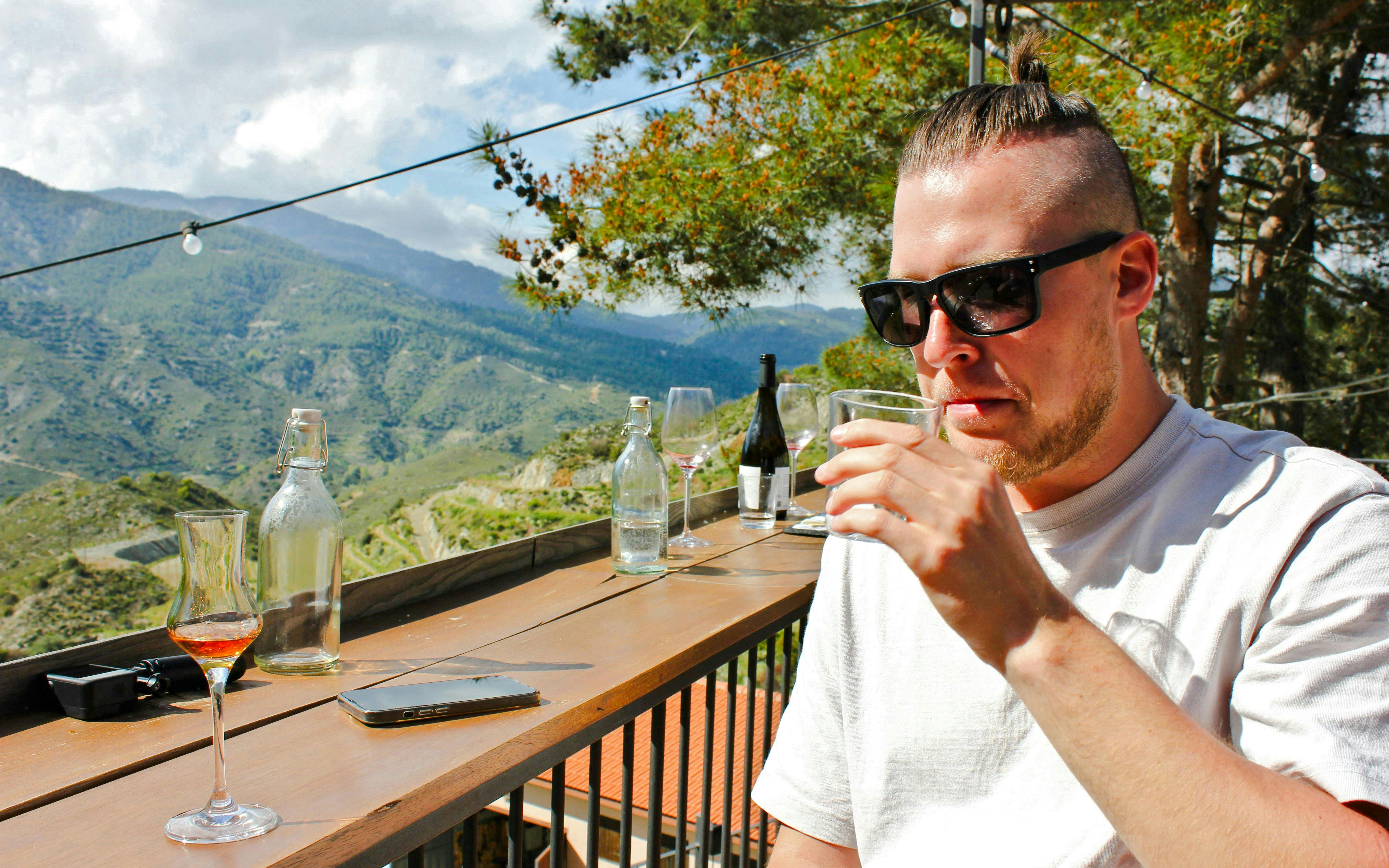 Man tasting wine with vineyard view at Tsiakkas Winery, Cyprus.
